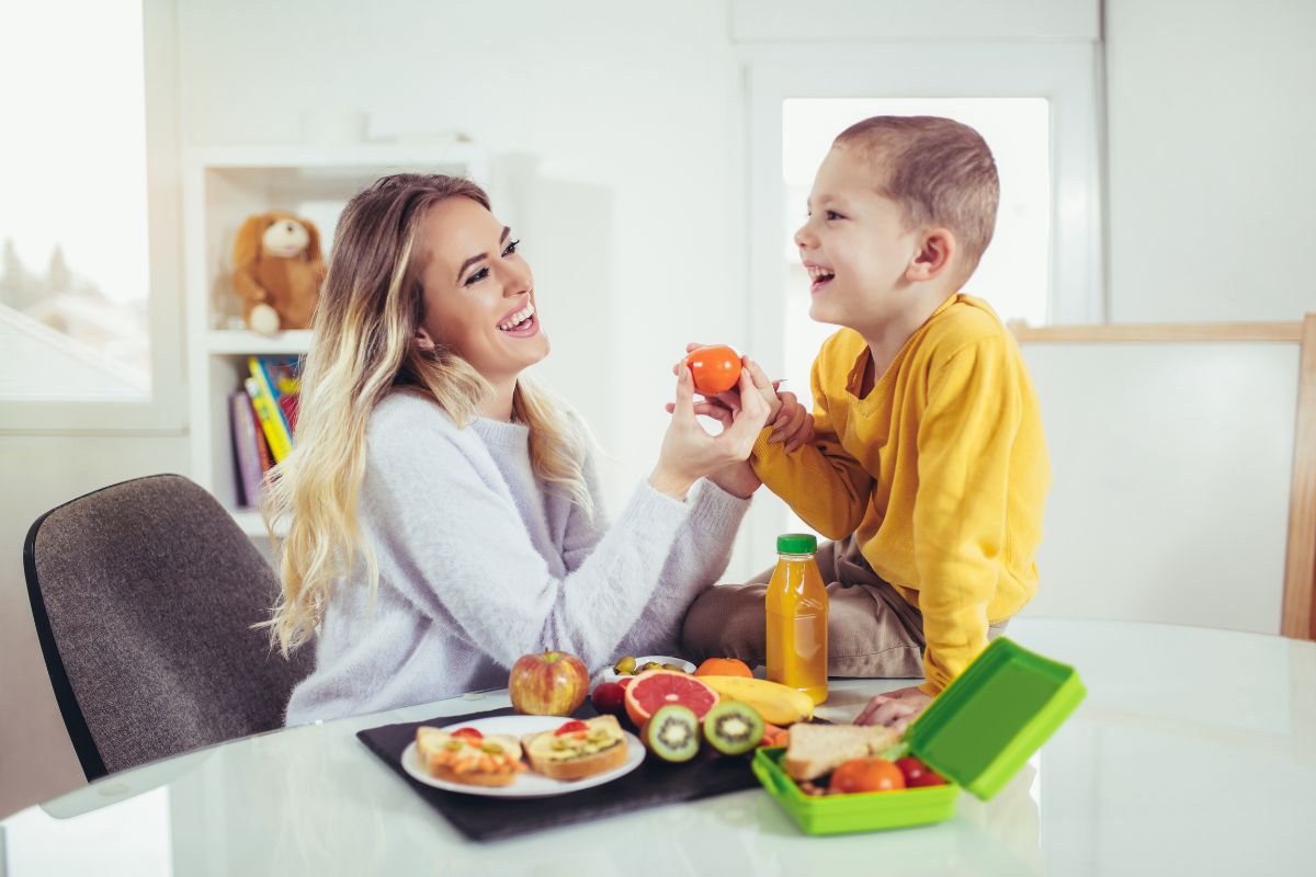 5 Healthy Snack Ideas Mother and child eating healthy food together at kitchen table in bright home setting.