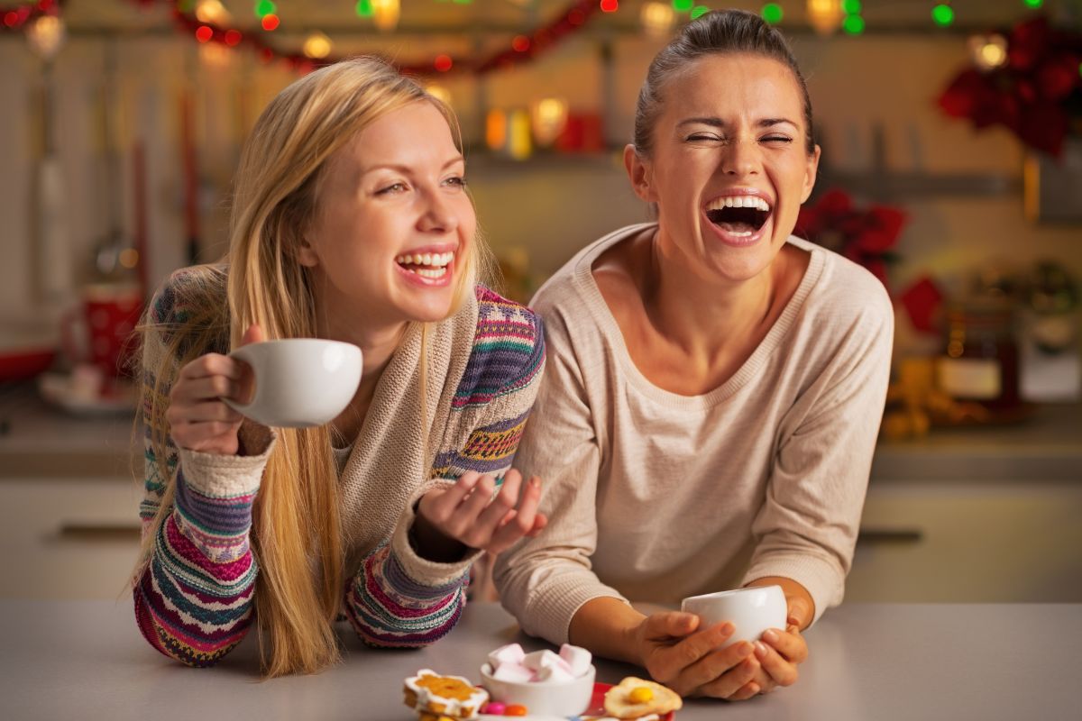 Happy couple holding mugs and cookies in festive Christmas living room setting.